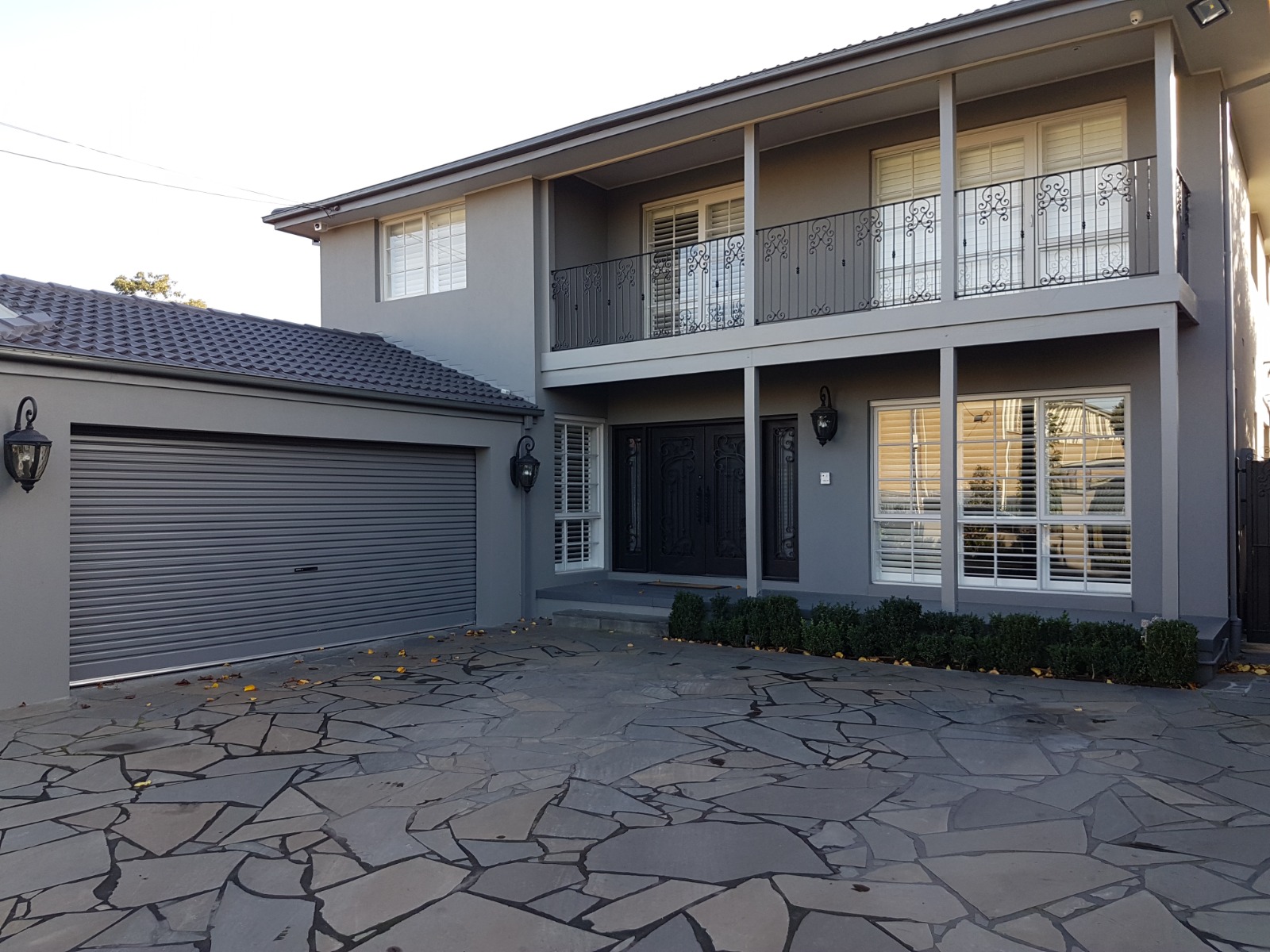 Rendered and textured brick veneer two-storey home in Essendon with balcony and rendered garage