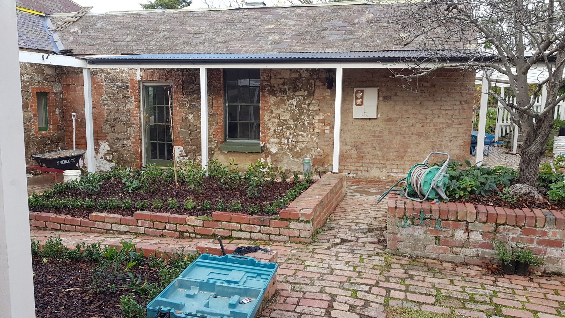 Courtyard elevation of Rosehill Homestead stripped of render, exposing stone and brick