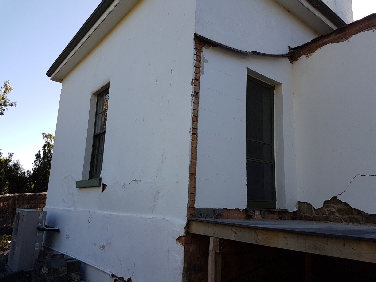 Cracked and failing render on the exterior wall of Rosehill Homestead before restoration