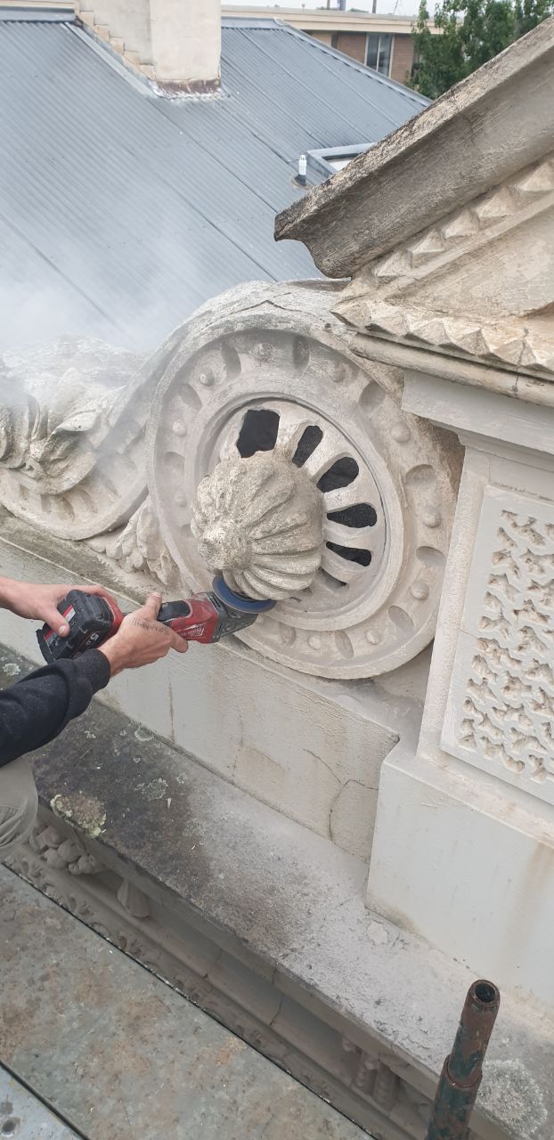 Decorative parapet scroll being carefully removed for reproduction